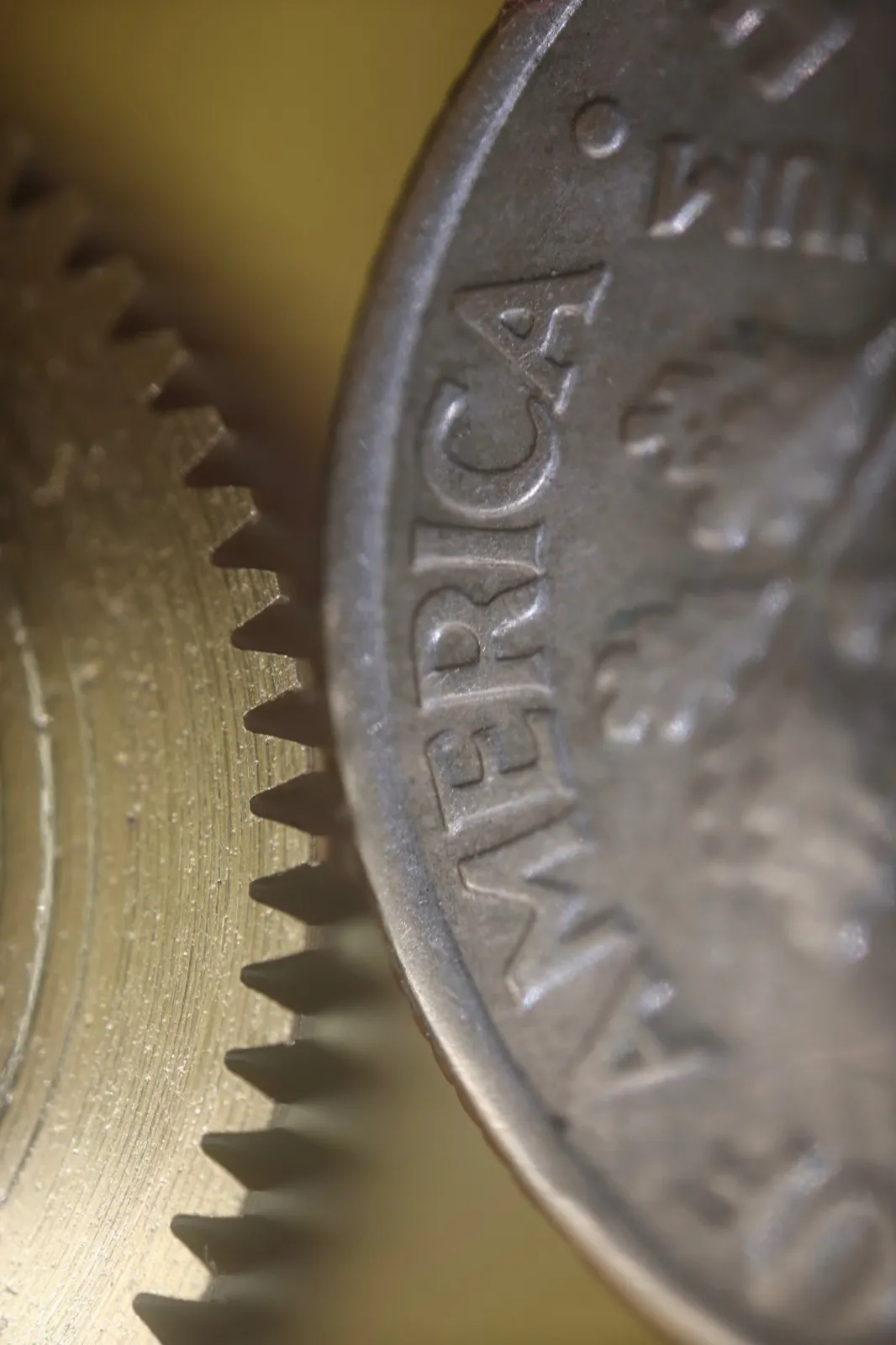 Close-up of fine-pitch gear teeth next to the edge of a coin